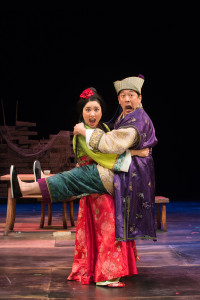 Blossom (Leah Anderson) and Master Yuan (Paul Juhn) in a compromising position in OSF’s Secret Love In Peach Blossom Land Photo by Jenny Graham.